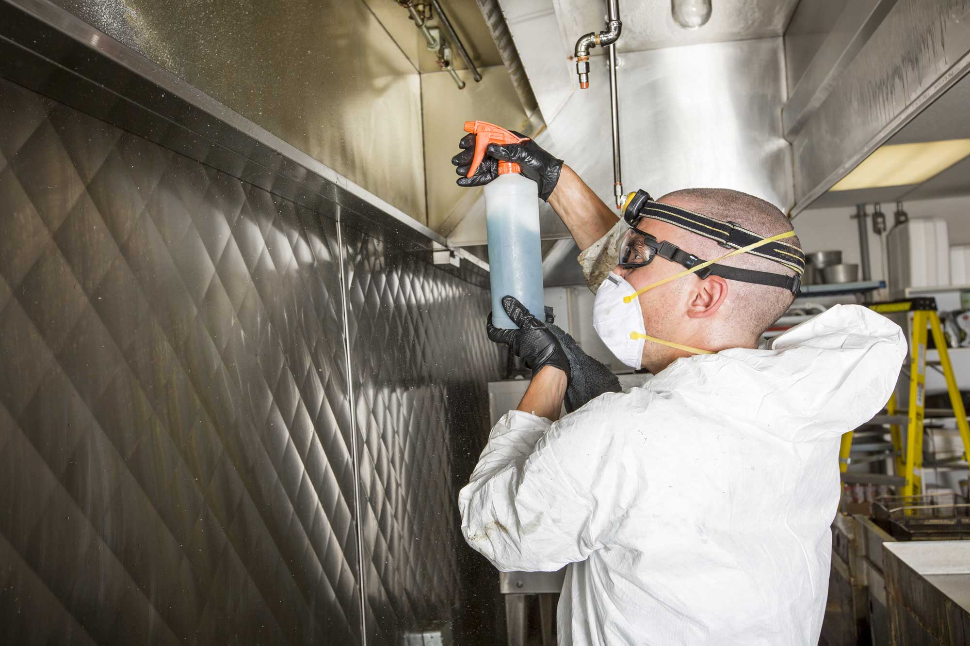 Man using a spray to clean ovens